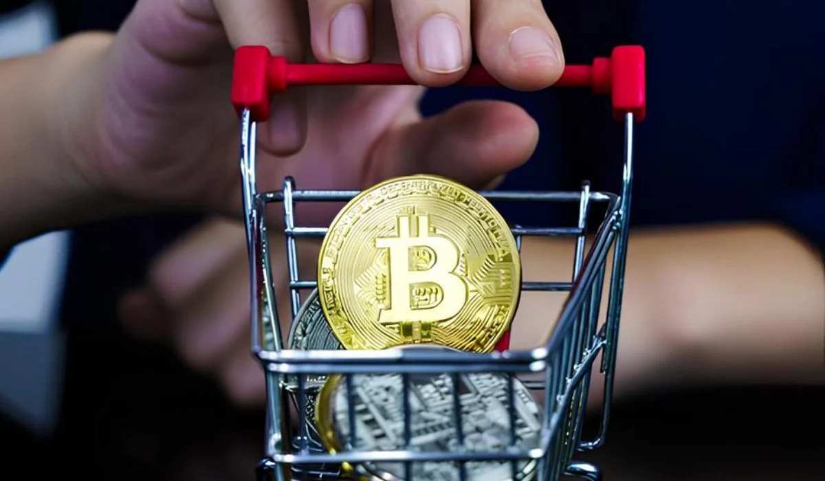 A person holding a shopping cart with crypto coins in it